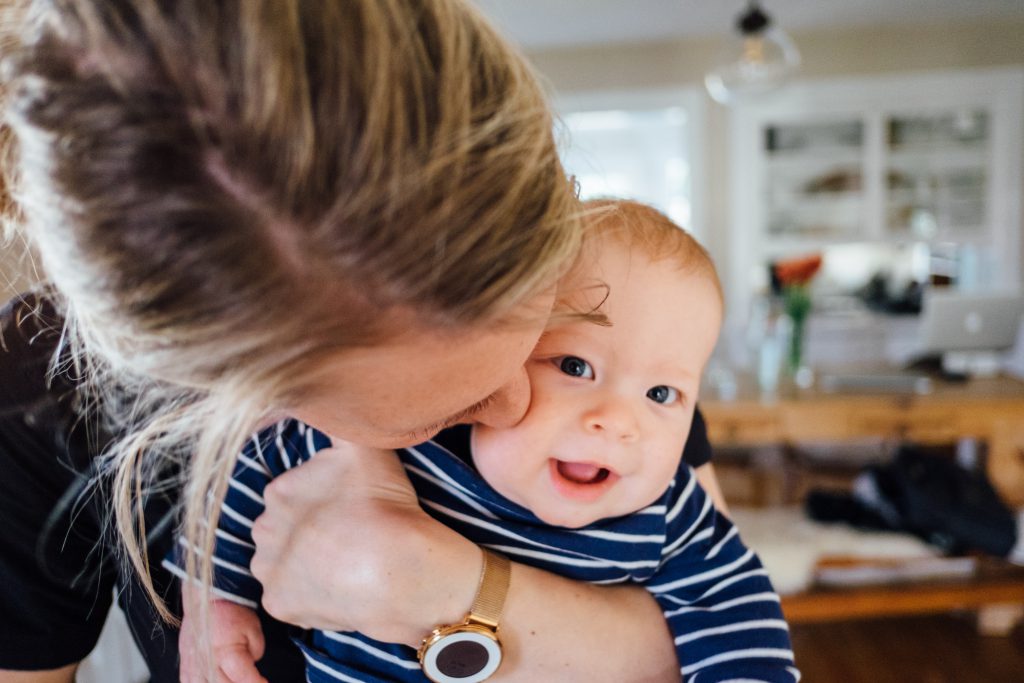 A woman kisses a smiling baby