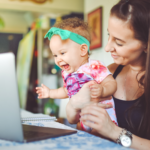 A woman holds a baby up to her laptop