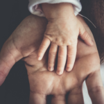 A small child's hand on top of an adult's hand