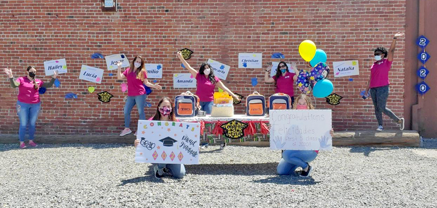 Teachers wearing masks strike celebratory poses, while two hold congratulatory posters